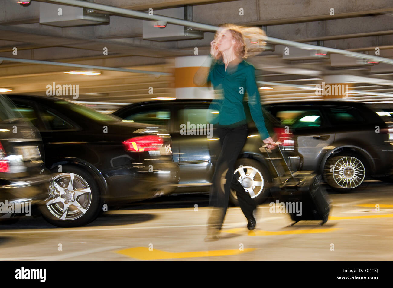 Jeune femme avec une valise roulant dans un parking couvert Banque D'Images