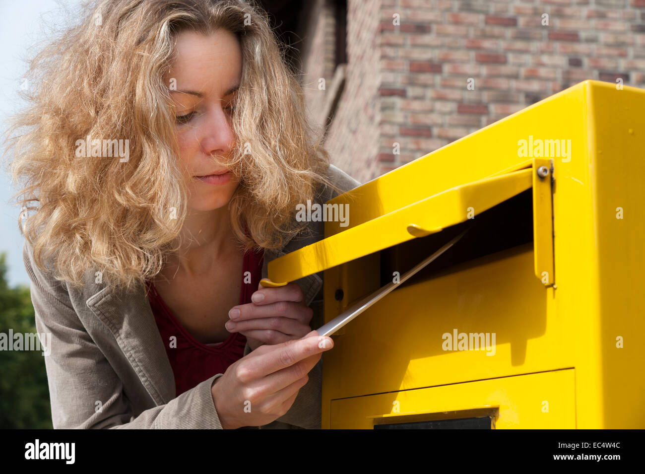 Jeune femme avec une lettre à une boîte aux lettres Banque D'Images