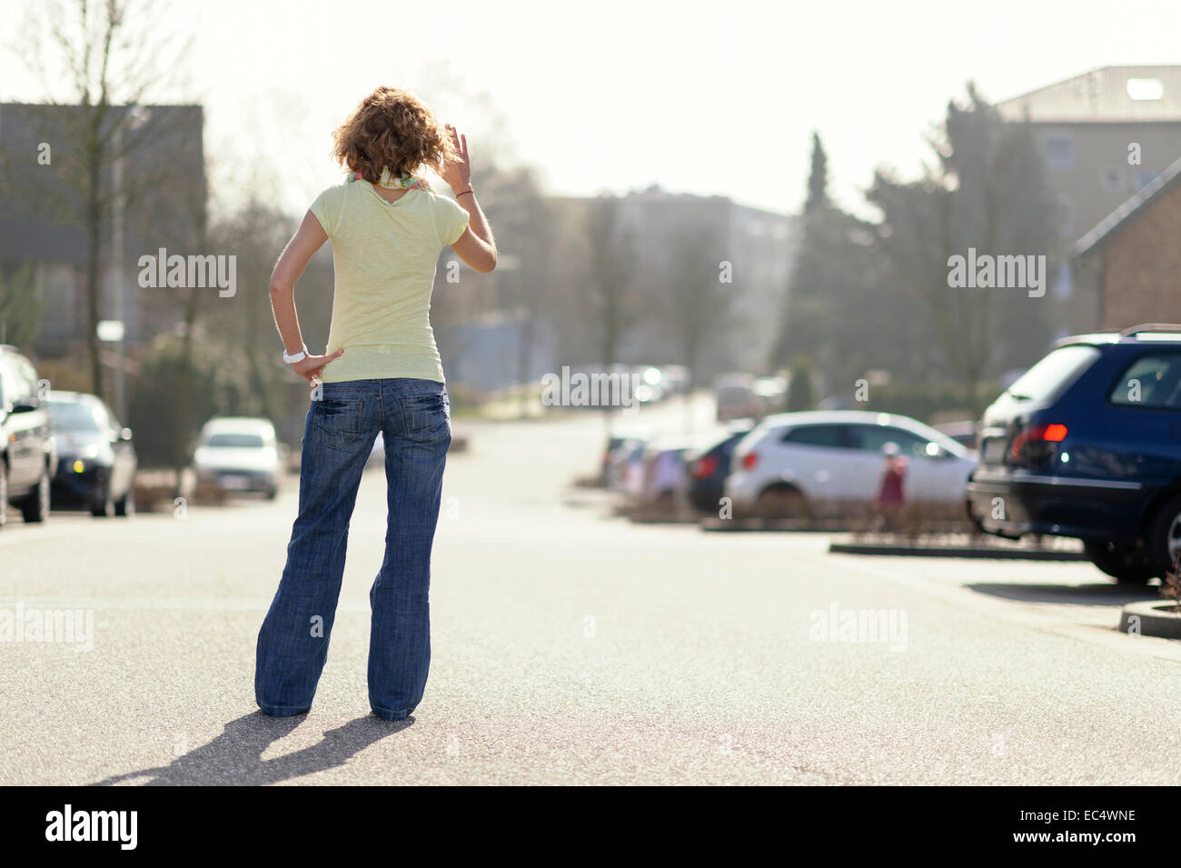 Jeune femme debout dans la rue, agitant à un enfant Banque D'Images