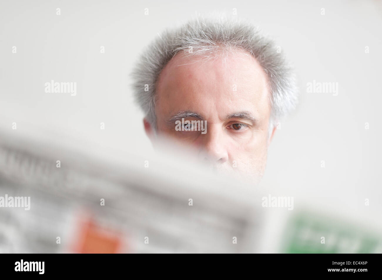 Un homme avec une expression faciale neutre reading a newspaper Banque D'Images
