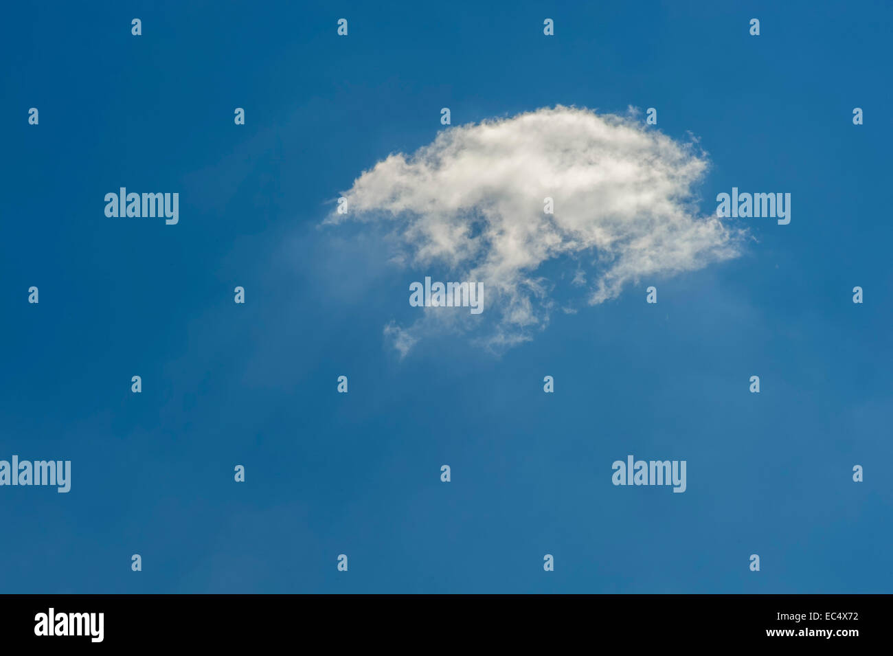Un petit nuage blanc contre un ciel bleu Banque D'Images