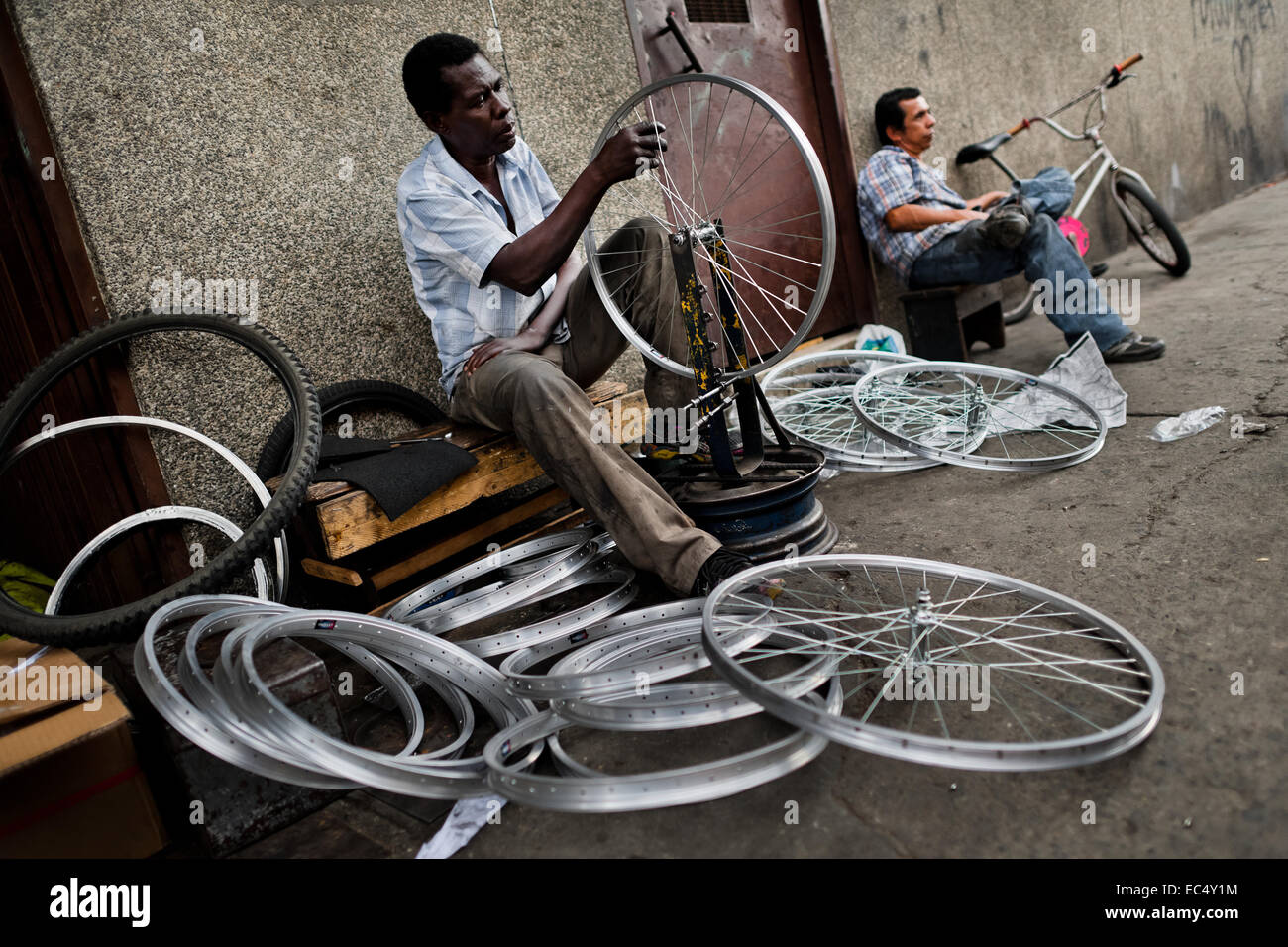 Un mécanicien vélo fonctionne avec une clé à rayons sur roue de vélo à  l'extérieur d'une petite usine de vélos à Cali, Colombie, le 27 juin 2014.  En raison de la forte