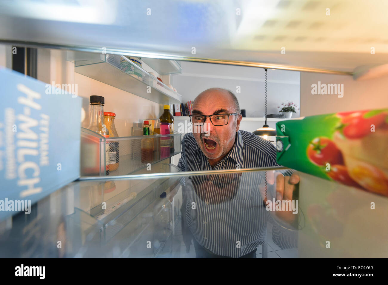Un cadre supérieur à la recherche à la recherche de la bière dans le réfrigérateur en colère Banque D'Images