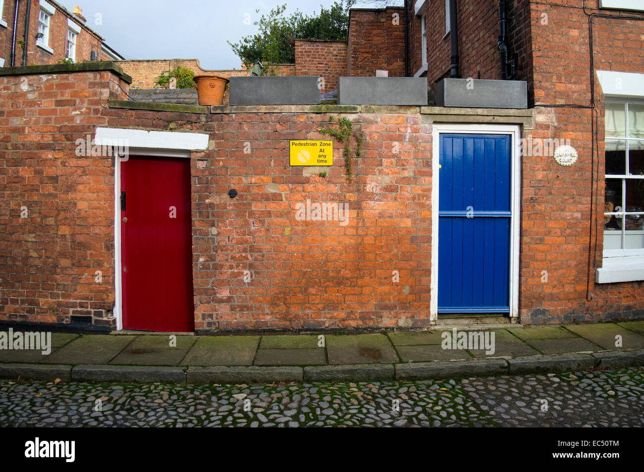 Portes en bois bleu et rouge dans un mur de brique à Swan Hill, Shrewsbury, Shropshire, Angleterre Banque D'Images
