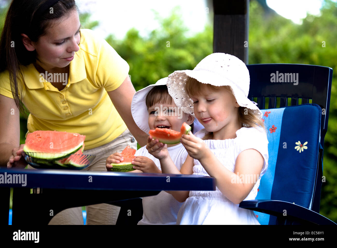 Un closeup portrait de deux jeunes sœurs leur mère manger pastèque mûre dans le jardin d'été Banque D'Images