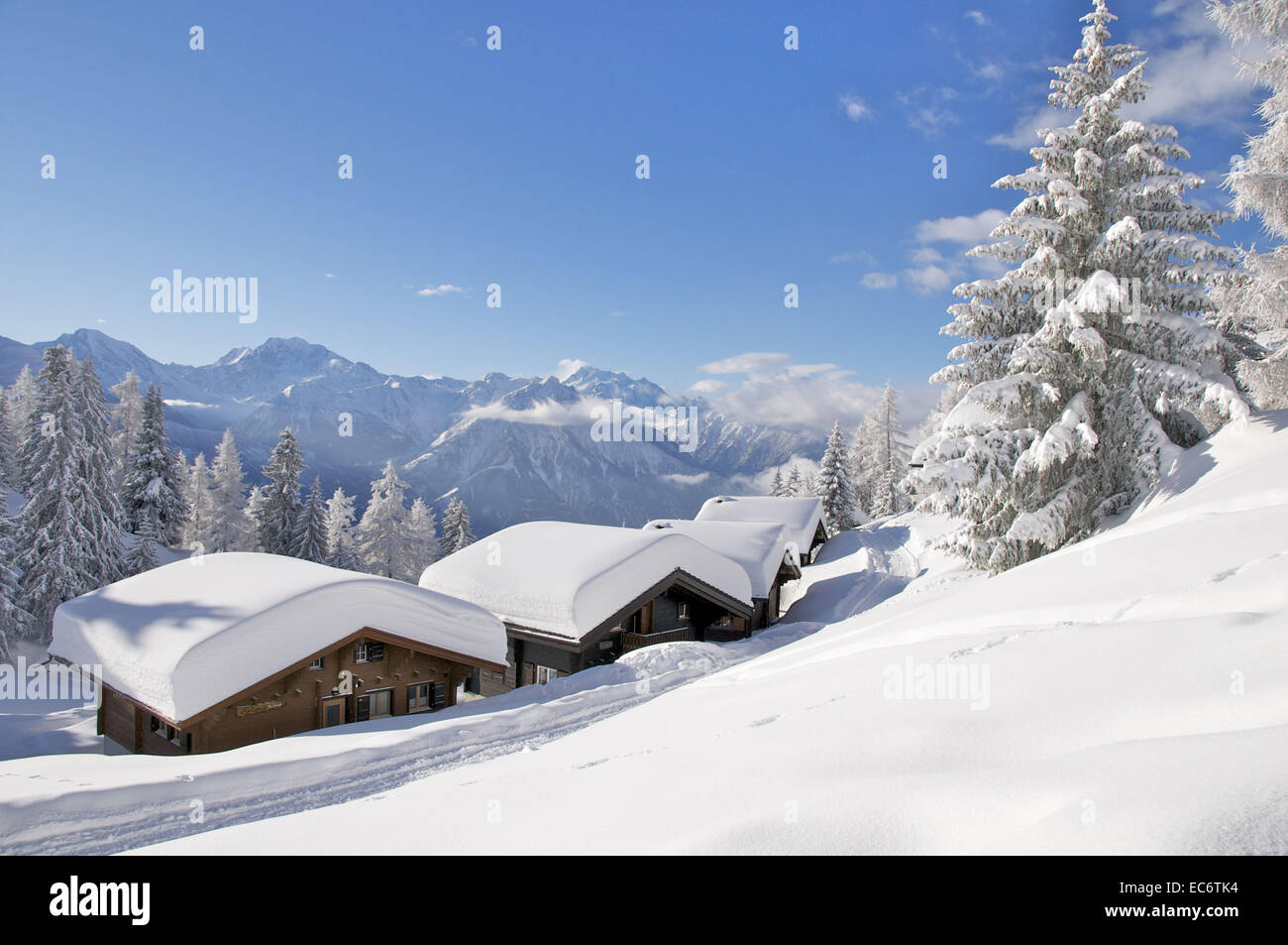 Par la neige fraîchement chalets sur Riederalp, montagnes blanches et bleu ciel à l'arrière-plan Banque D'Images