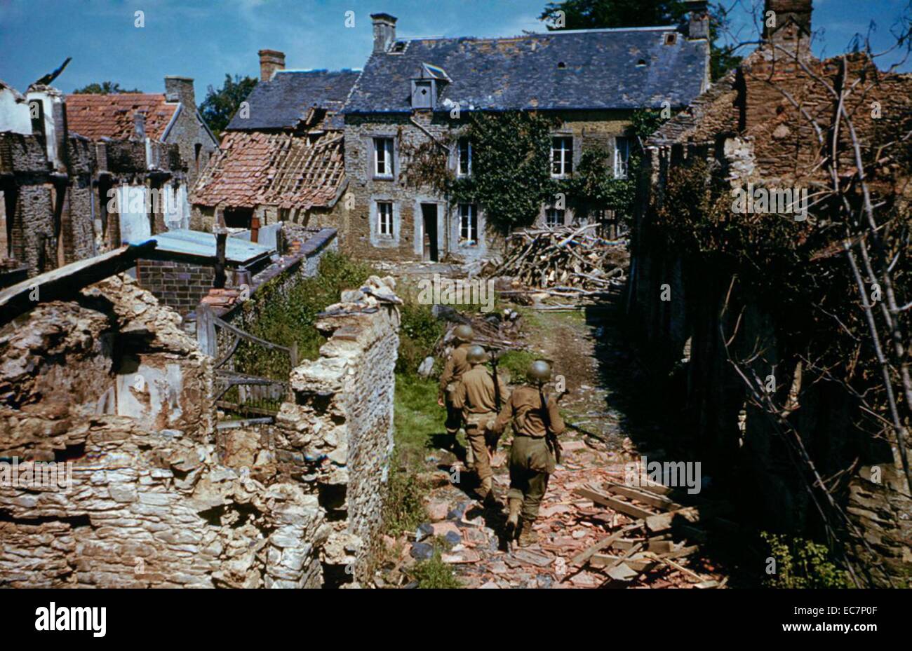 Photographie couleur de soldats américains patrouillant dans un village français. Datée 1944 Banque D'Images