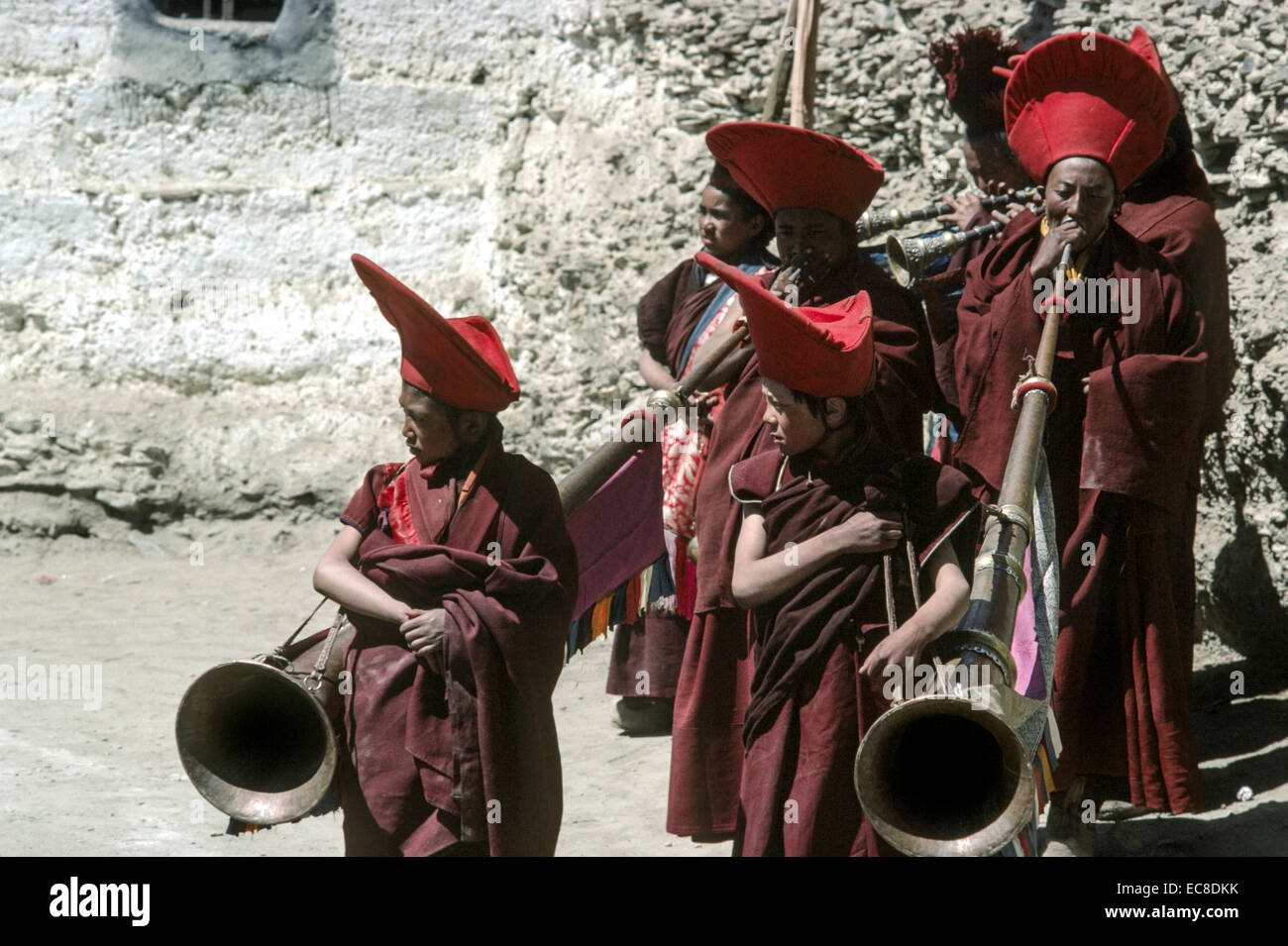 Ladakh monastère red hat courtyard des moines du Tibet jouer longues cornes en laiton gonchas soleil rouge robes hommes garçons Banque D'Images