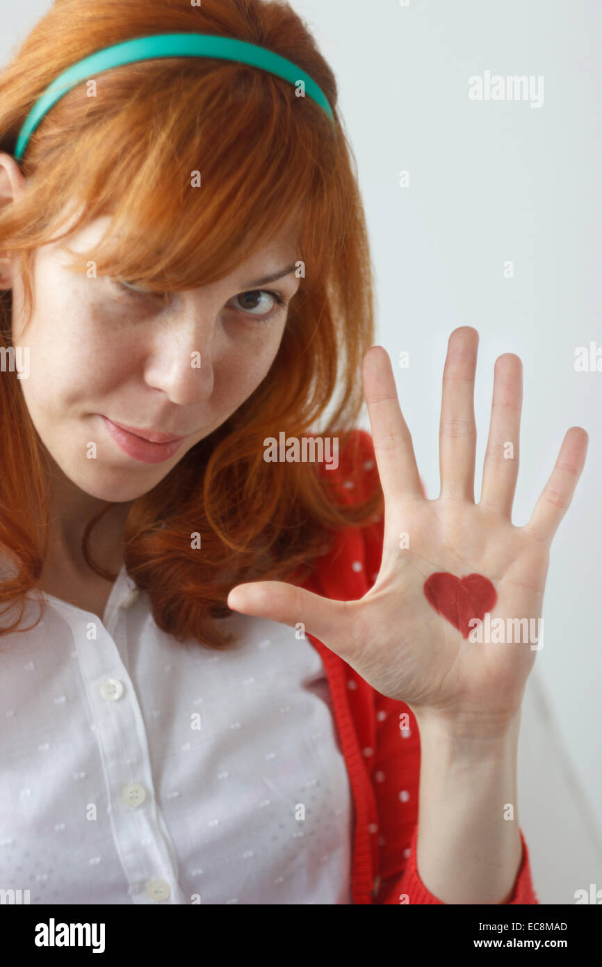 Cute girl rousse montrant coeur peint sur sa paume Banque D'Images