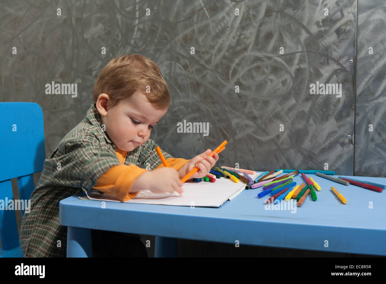 Enfant assis à une table à dessiner avec des marqueurs de couleur Banque D'Images