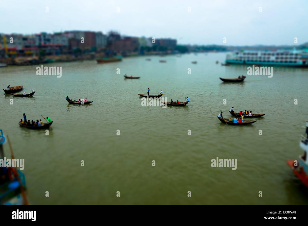 Les personnes transportant des passagers des bateaux en bois à travers une rivière à Dhaka, Bangladesh Banque D'Images