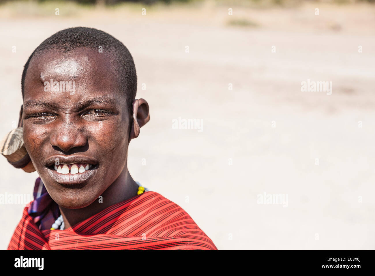 Image d'un jeune homme de la tribu Masaï avec d'immenses ouvertures dans ses lobes d'oreille de porter plus de bouchons d'oreilles en bois de taille moyenne. Banque D'Images