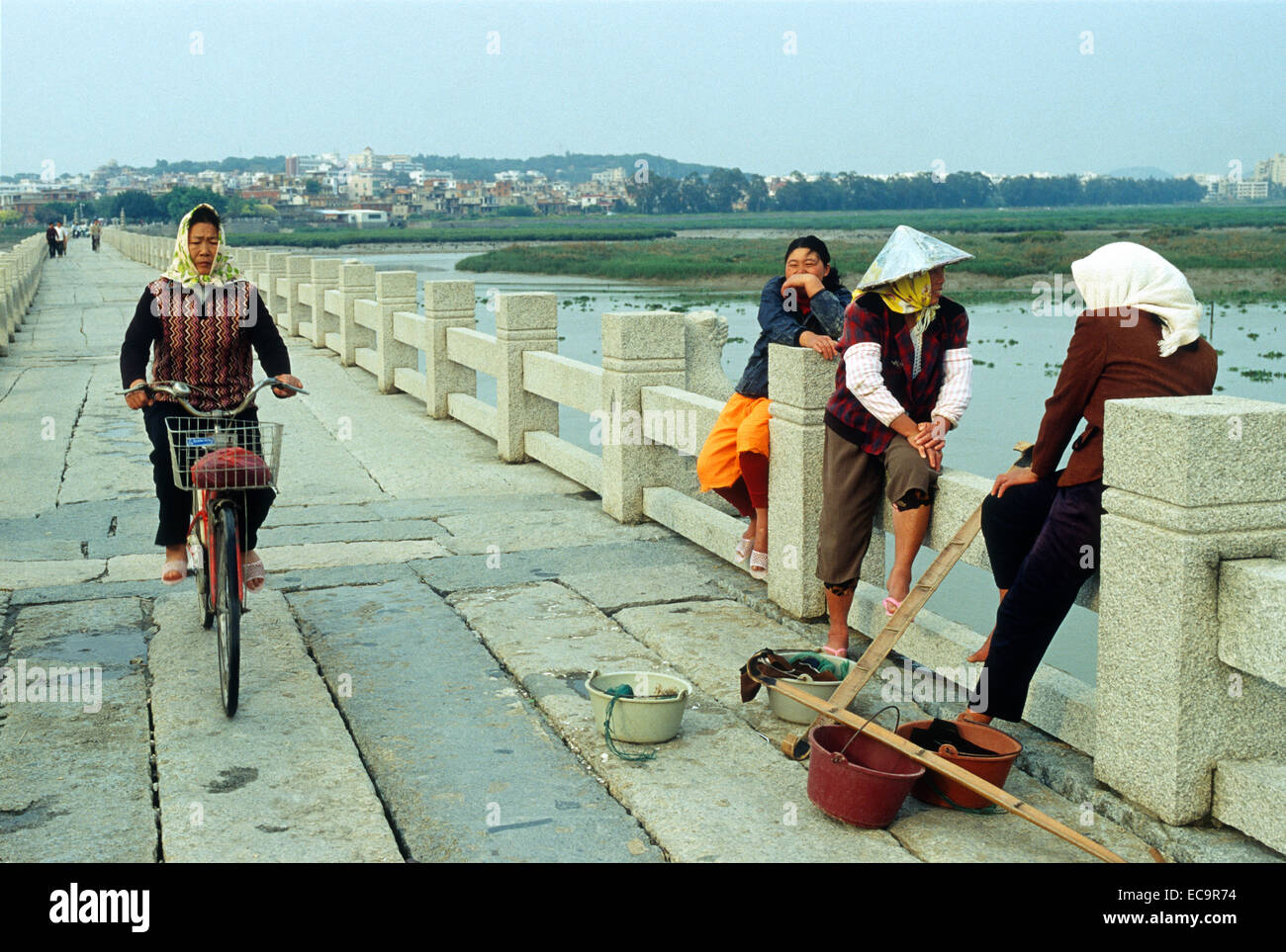 Une femme monte un Xiamen location alors que les trois autres reste sur Luoyang Bridge à Quanzhou, Fujian, Chine. 13-Apr-2009 Banque D'Images
