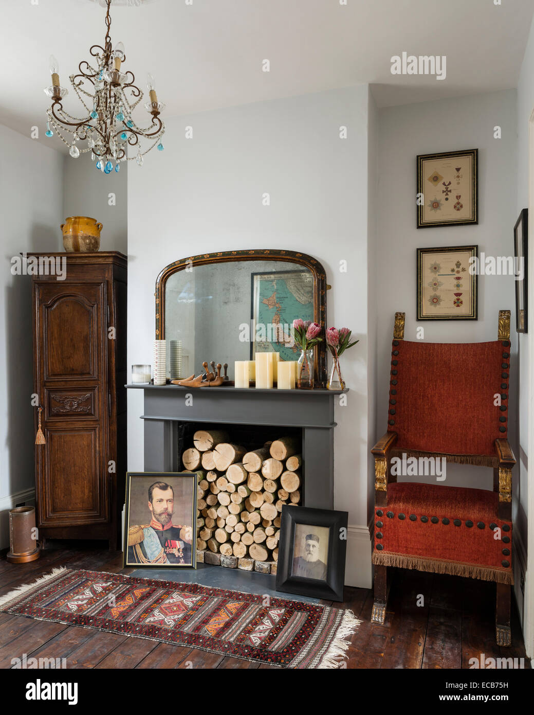 Tapis Vintage sur plancher en bois en face d'une cheminée avec des bûches et des portraits de famille Banque D'Images