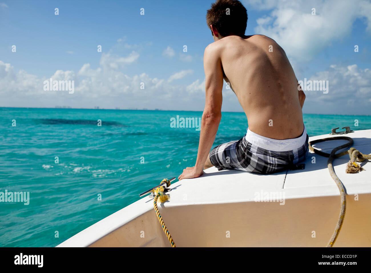 Un jeune homme assis sur la proue d'un bateau de plongée à Isla Mujeres, au Mexique. Banque D'Images