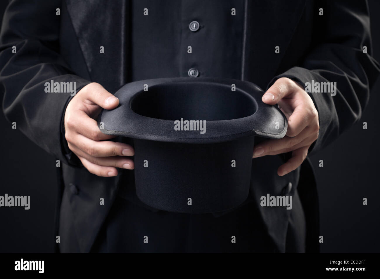 Gros plan du top hat en magicien mains isolé sur fond sombre Banque D'Images