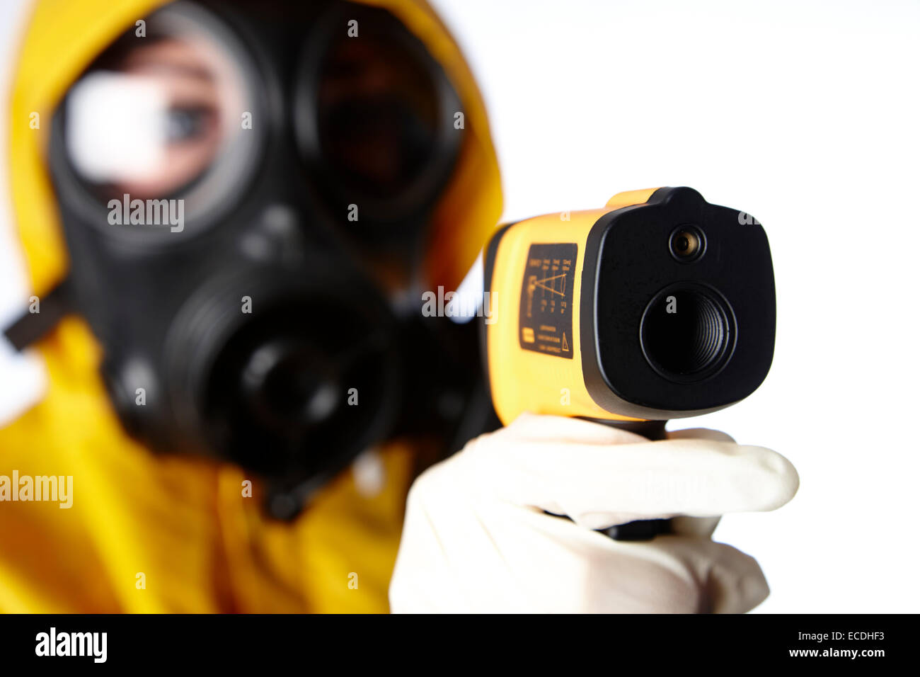 femme portant des vêtements de protection et un masque à gaz protection du visage à l'aide d'un thermomètre infrarouge pour vérifier les symptômes de fièvre du virus de la grippe dans un concept pandémique Banque D'Images