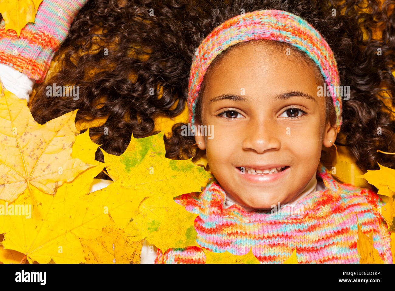 Jeune fille africaine avec des cheveux bouclés dans les feuilles d'orange Banque D'Images