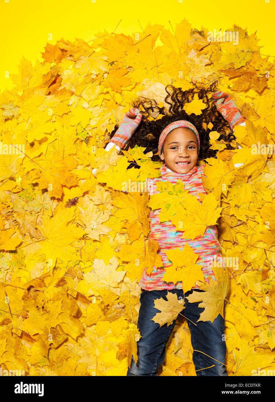 Petite fille africaine recouverte de feuilles d'automne Banque D'Images