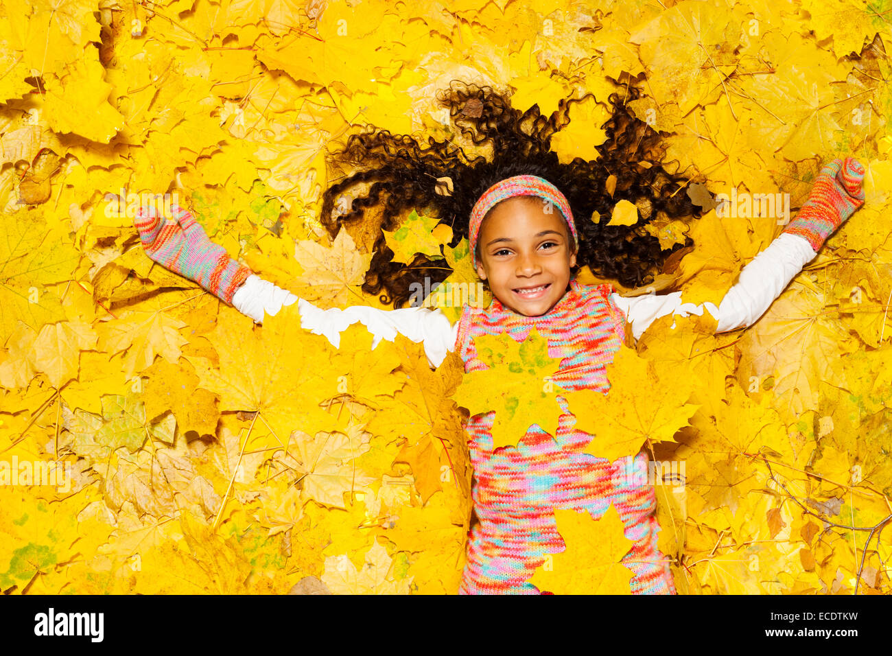 Peu de petite fille africaine sous jaune feuilles d'érable Banque D'Images