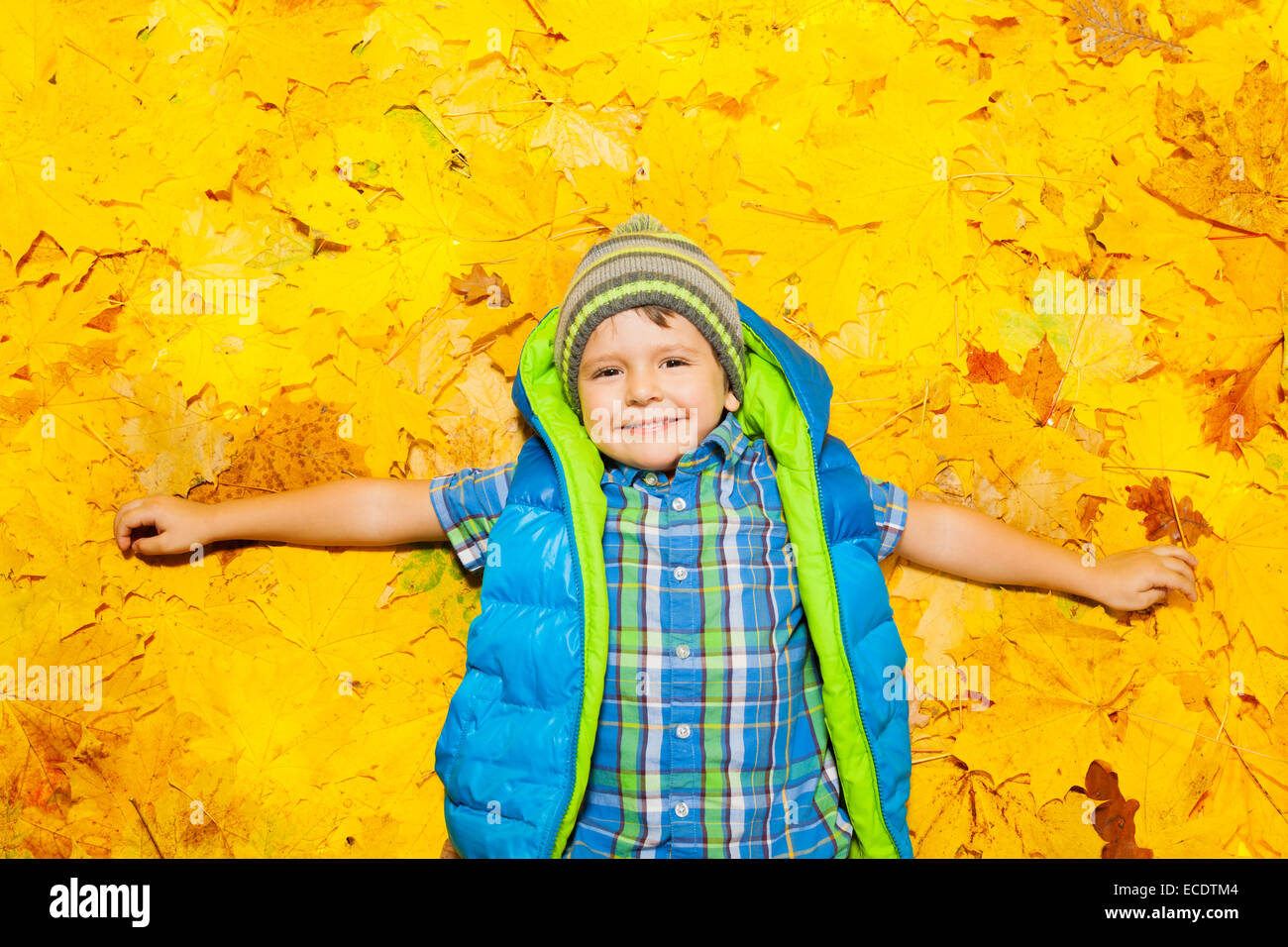 Happy boy laying en orange les feuilles d'automne Banque D'Images