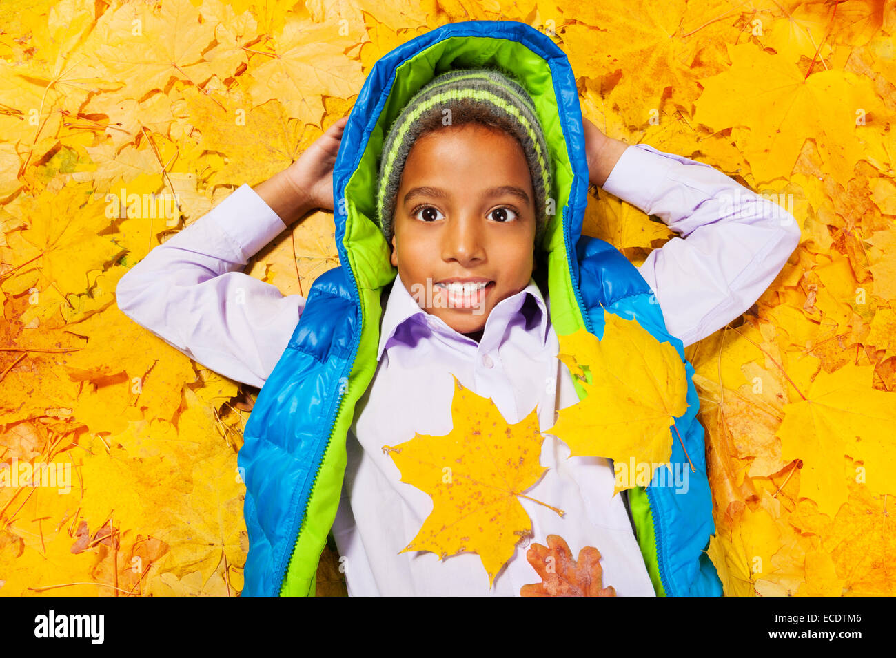 African boy jette en tas de feuilles d'automne Banque D'Images
