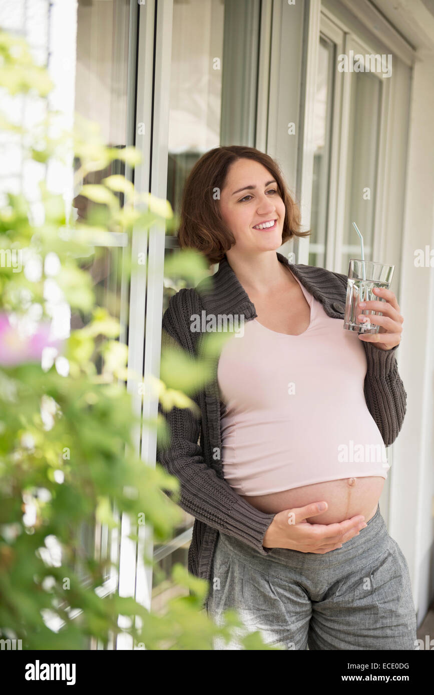 Terrasse heureux femme enceinte portrait de l'eau en verre Banque D'Images