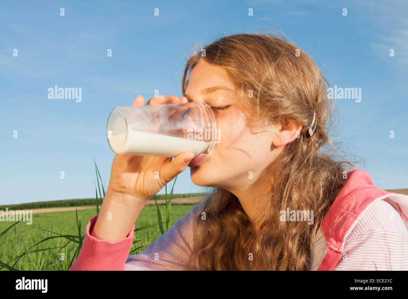 Girl (12-13), de boire dans un verre de lait à l'extérieur, les yeux clos, portrait Banque D'Images