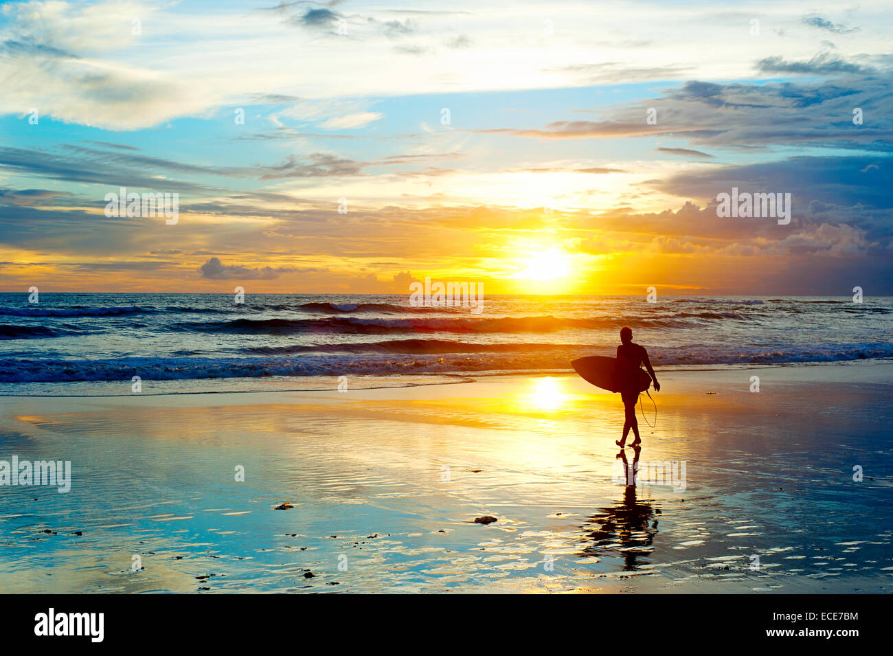Surfeur sur la plage au coucher du soleil sur l'île de Bali, Indonésie Banque D'Images