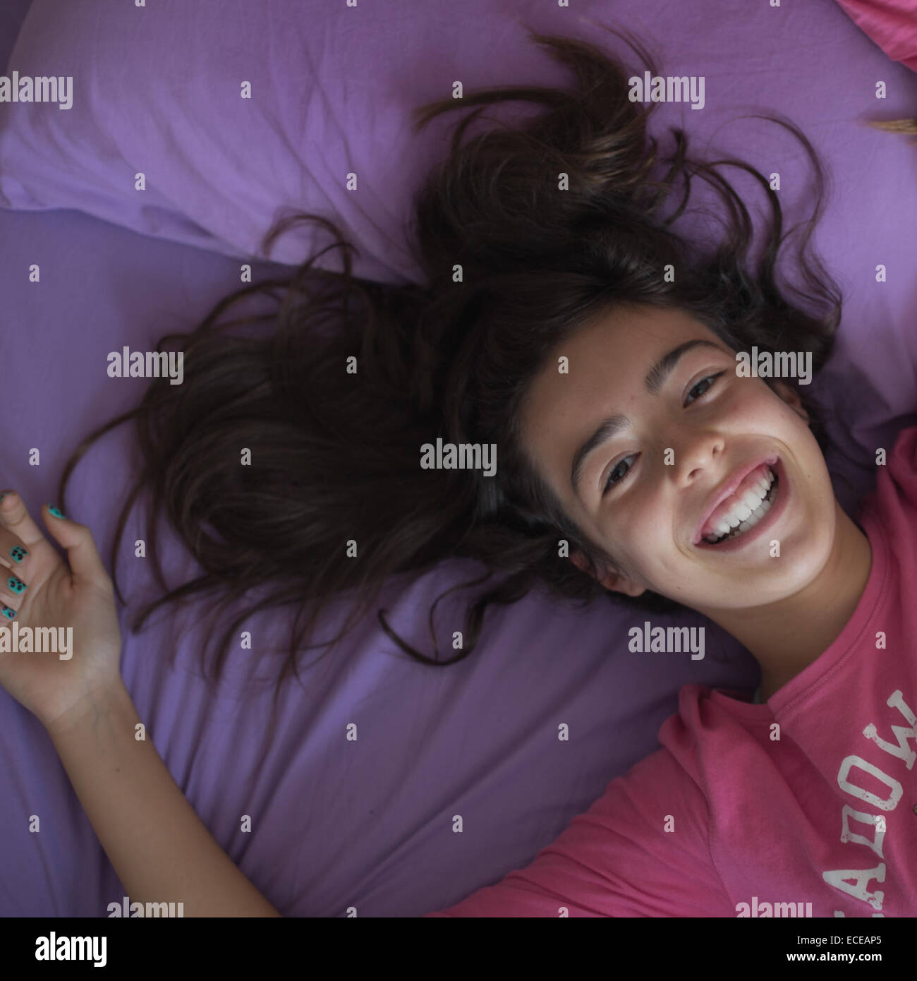 Girl lying on bed smiling Banque D'Images