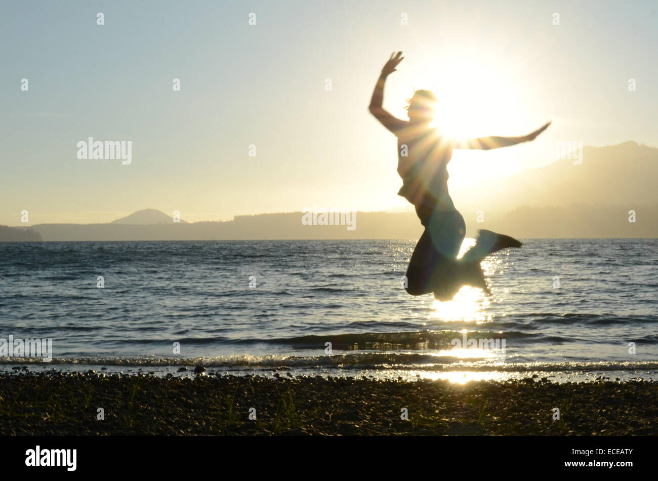 L'État de Washington, USA, Olympic National Park, photo d'action de silhouette de femme sautant sur la plage au coucher du soleil Banque D'Images