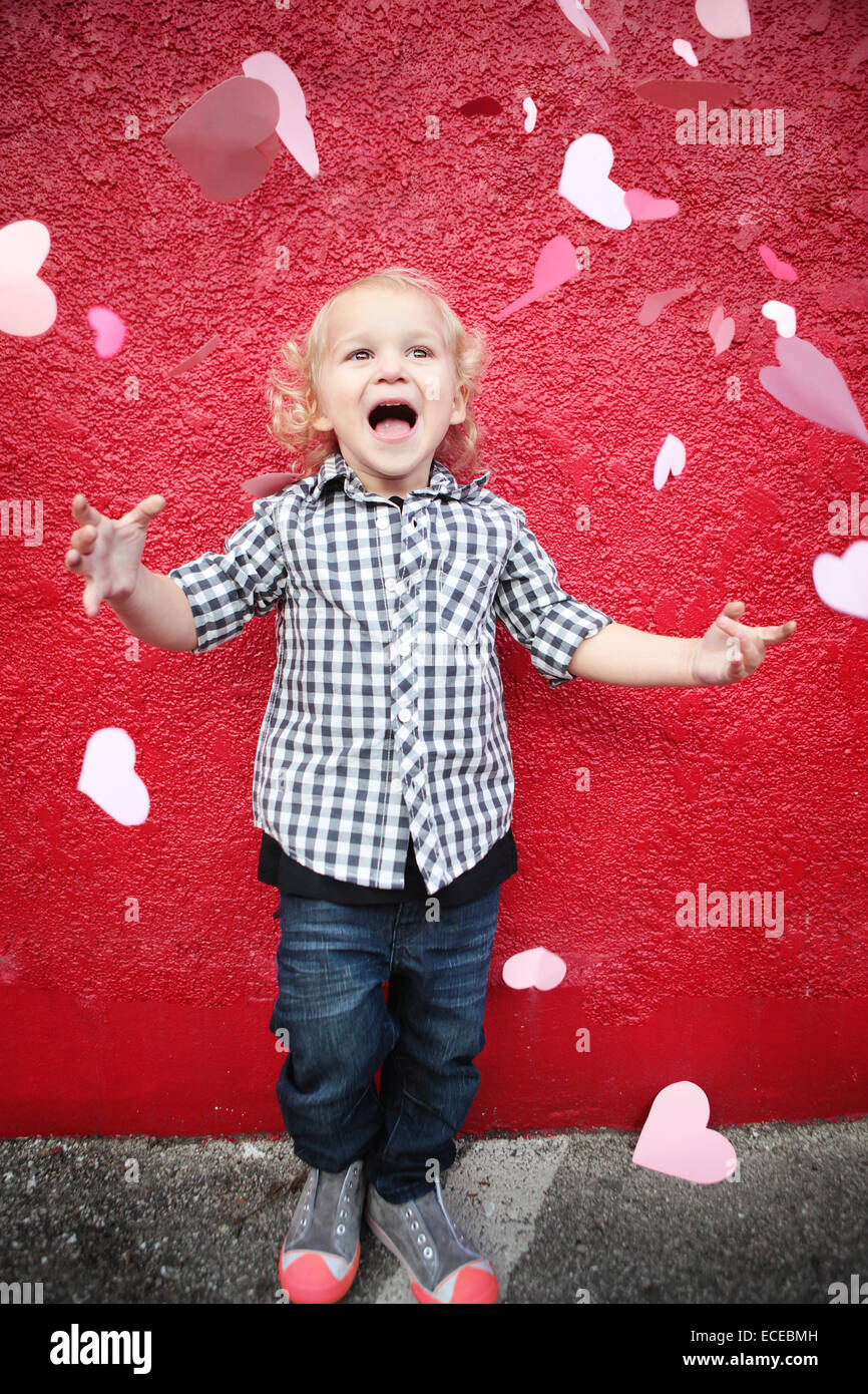 Boy throwing paper hearts dans l'air Banque D'Images