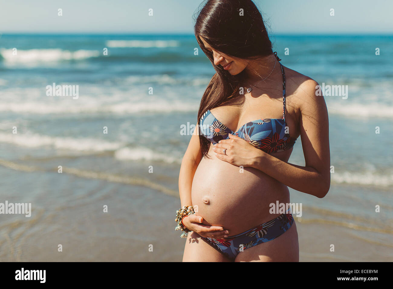 Young pregnant woman standing on beach Banque D'Images