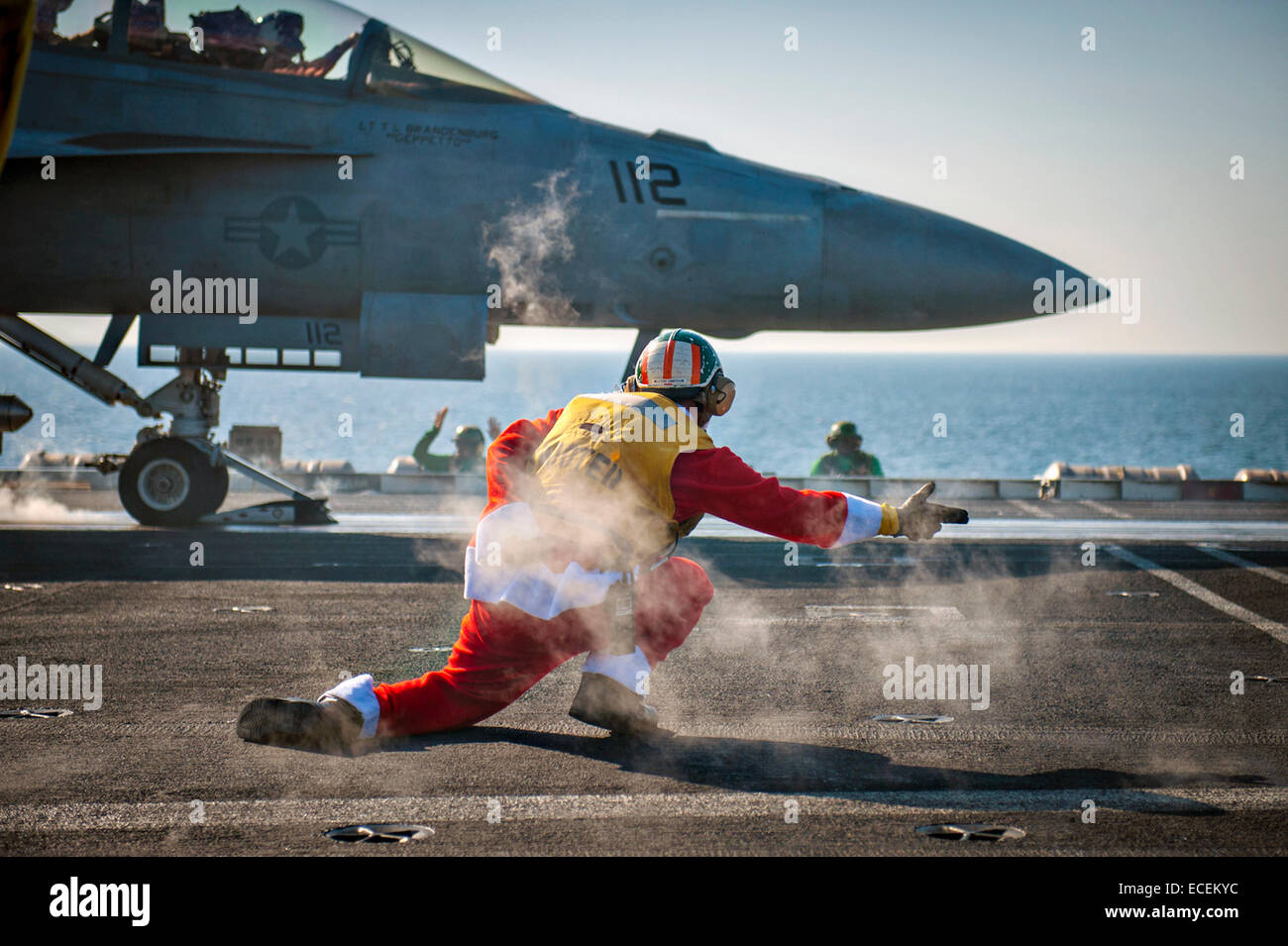 Un marin de l'US Navy portant un costume de Père Noël est un shooter de vol alors qu'il lance un F/A-18F Super Hornet dans le poste de pilotage à bord de la classe Nimitz porte-avions USS Carl Vinson, 12 décembre 2014 dans la région du Golfe. Le navire est un soutien à l'opération d'opérations inhérentes à résoudre, en Iraq et en Syrie contre l'Etat islamique d'objectifs. Banque D'Images