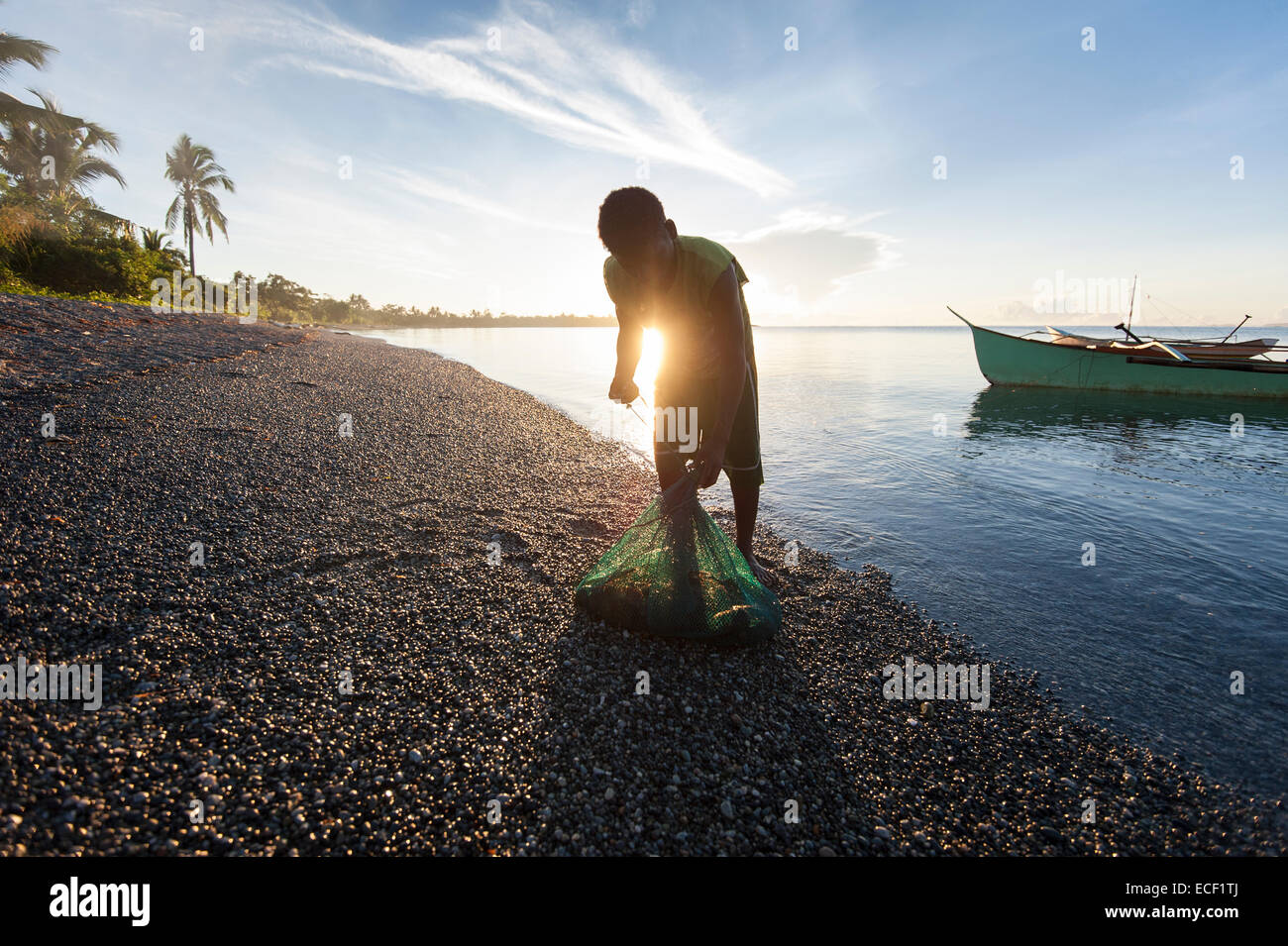L'agta un homme portant dans ses prises de homard en soirée sur la plage tôt le matin Banque D'Images