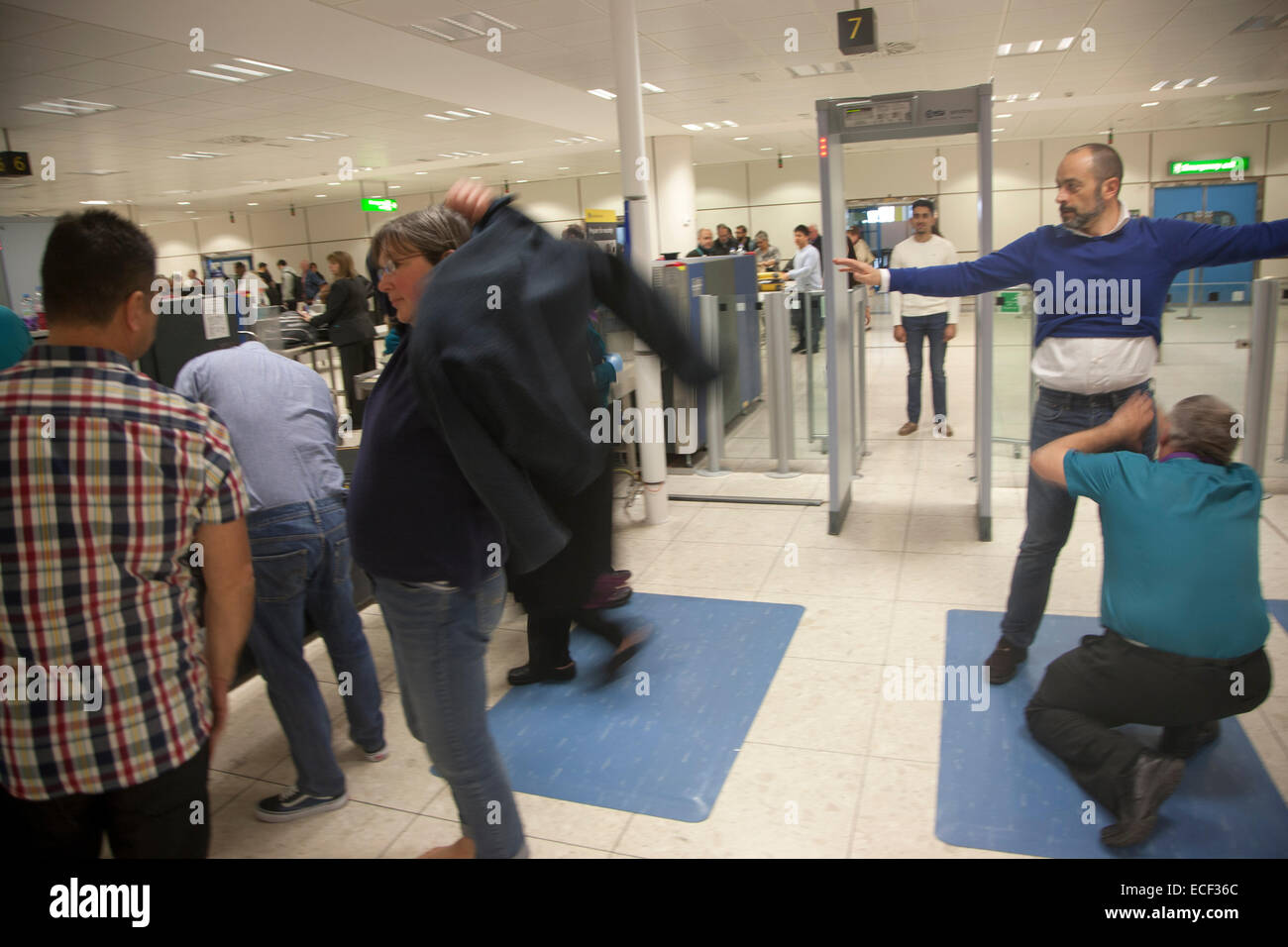 Les gens qui passent à travers le contrôle de sécurité à l'aéroport de Gatwick, England, UK Banque D'Images