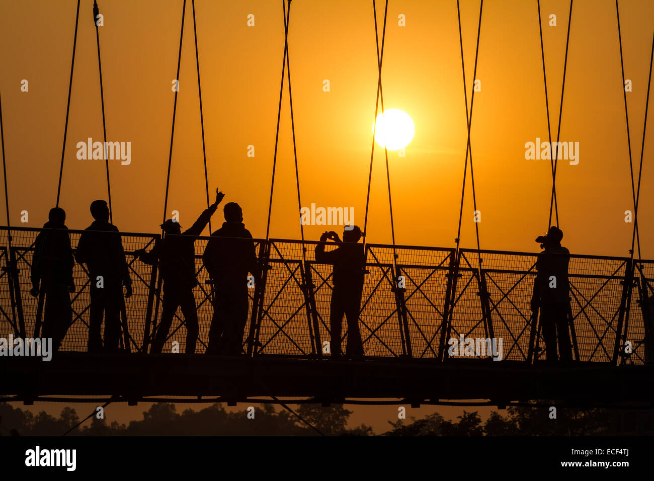 Les gens silhouettes sur le coucher du soleil, le Lakshman Jhula pont sur le Gange à Rishikesh, Inde. Banque D'Images