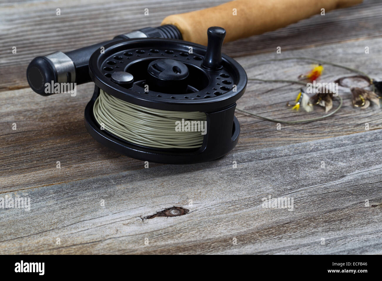 Close up of fly reel, se concentrer sur l'avant fond de bobine, avec bouchon partiel pôle traitées et les mouches floue sur planche de bois rustique Banque D'Images