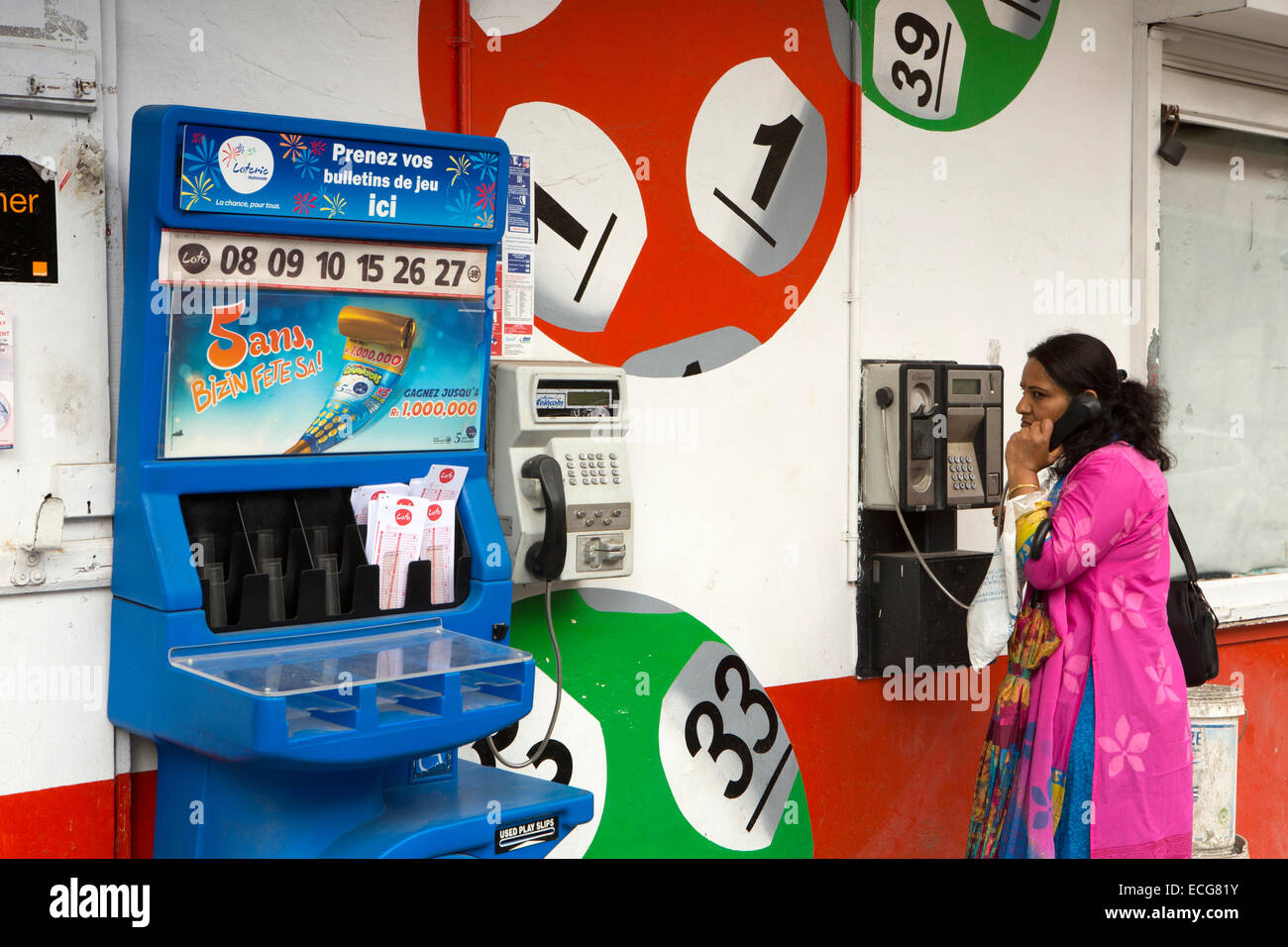 L'Ile Maurice, Mahebourg, du centre-ville, woman on téléphone public avec Lotto bâtiment décoré avec des boules de loterie Banque D'Images