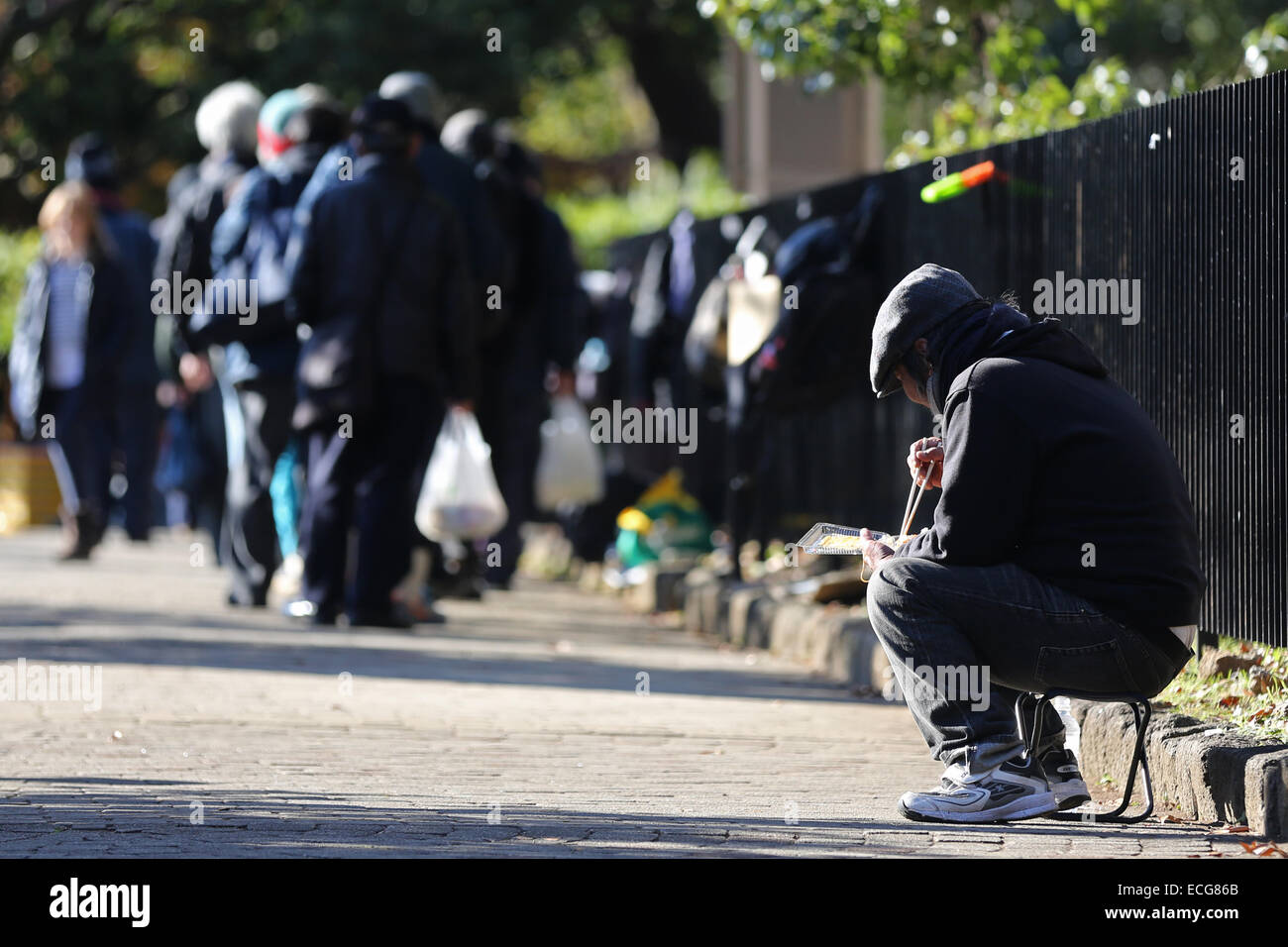 Un homme sans foyer consomme des aliments qu'il a reçu de la soupe populaire au Parc Yoyogi, à Tokyo, au Japon, le samedi, Décembre 13, 2014. (Photo par Yuriko Nakao/AFLO) Banque D'Images