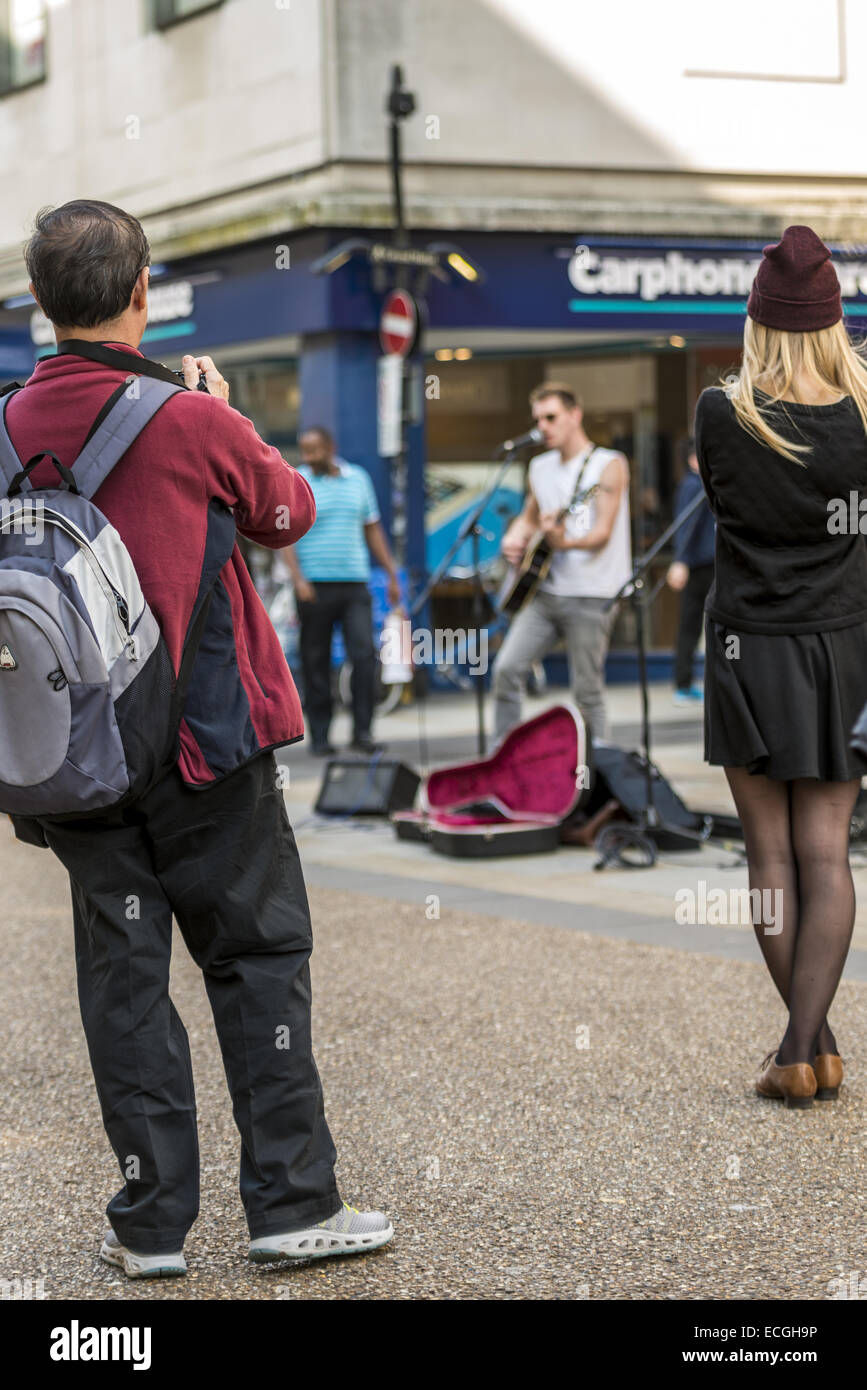 Passants prendre photo de street artiste du spectacle de jeunes musiciens sur Cornmarket Street, Oxford Banque D'Images