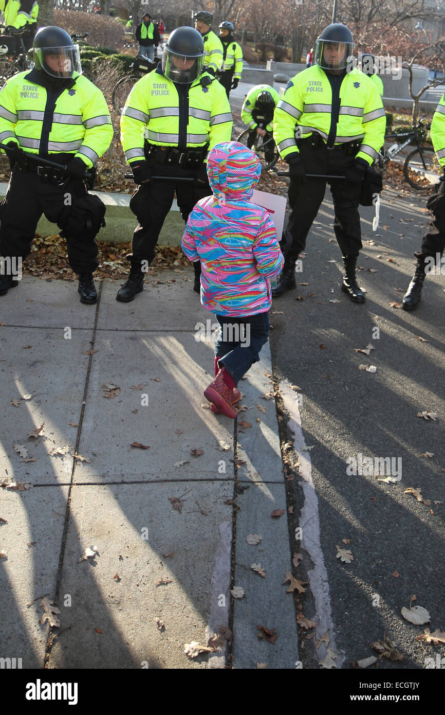 Boston, Massachusetts, USA. 13 Décembre, 2014. Un enfant marche jusqu'à une ligne de Massachusetts State Police près de la rue Nashua Prison, où les manifestants se sont réunis pendant les millions Mars rassemblement à Boston, Massachusetts, USA. La protestation, comme ceux d'autres villes aux États-Unis en ce jour, est en réponse aux récentes décisions du grand jury de ne pas inculper les policiers qui ont tué les hommes noirs non armés Michael Brown et Eric Garner, et pour les problèmes de longue date le racisme et la brutalité policière. Crédit : Susan Pease/Alamy Live News Banque D'Images