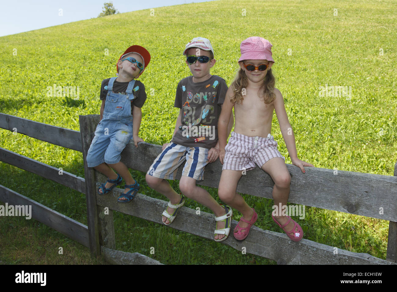 Trois enfants assis sur fence Banque D'Images
