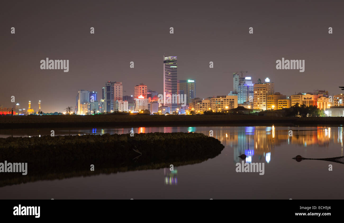 Nuit sur les toits de la ville, à l'éclat des lumières et des reflets dans l'eau. Manama, la capitale du Royaume de Bahreïn, au Moyen-Orient Banque D'Images