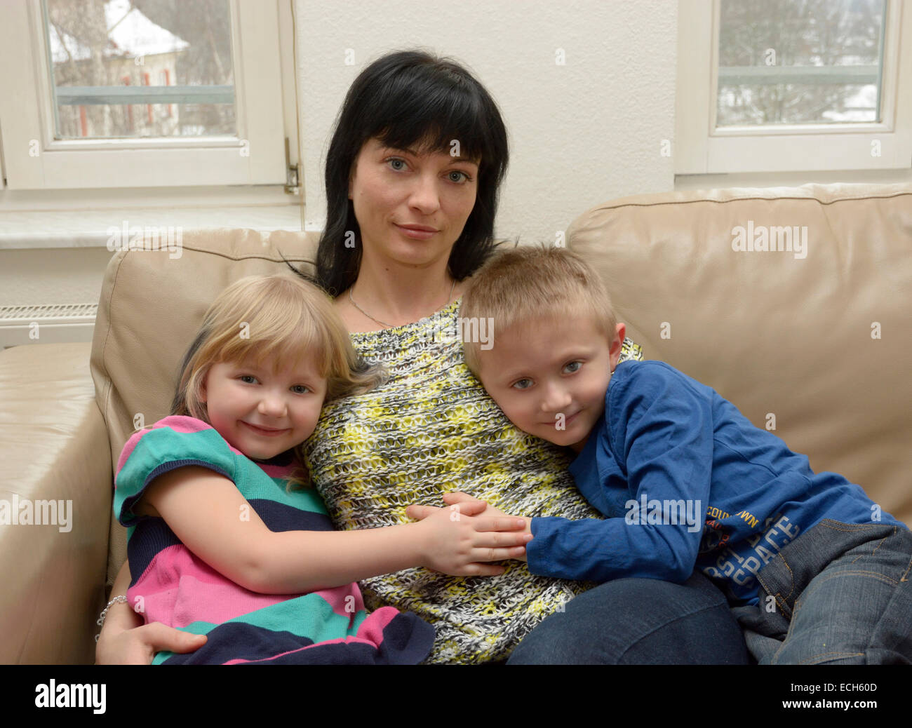 Fille, 5 ans, garçon, 7 ans avec leur mère, 35 ans, assis sur un canapé Banque D'Images