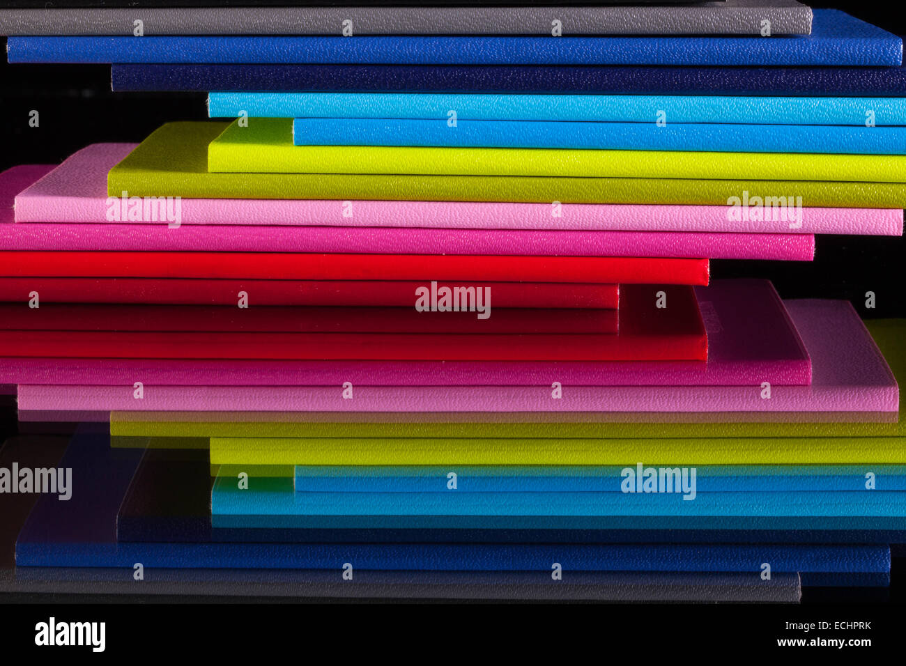 Douze journaux de différentes couleurs sur un bureau en verre Banque D'Images