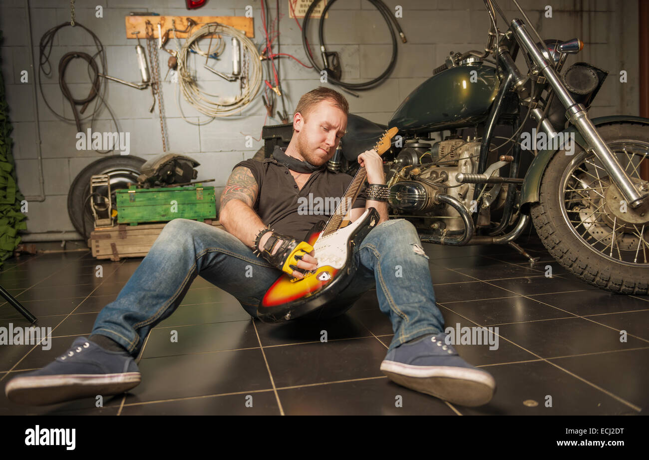 Man playing guitar rock music sur l'arrière-plan de la moto Banque D'Images