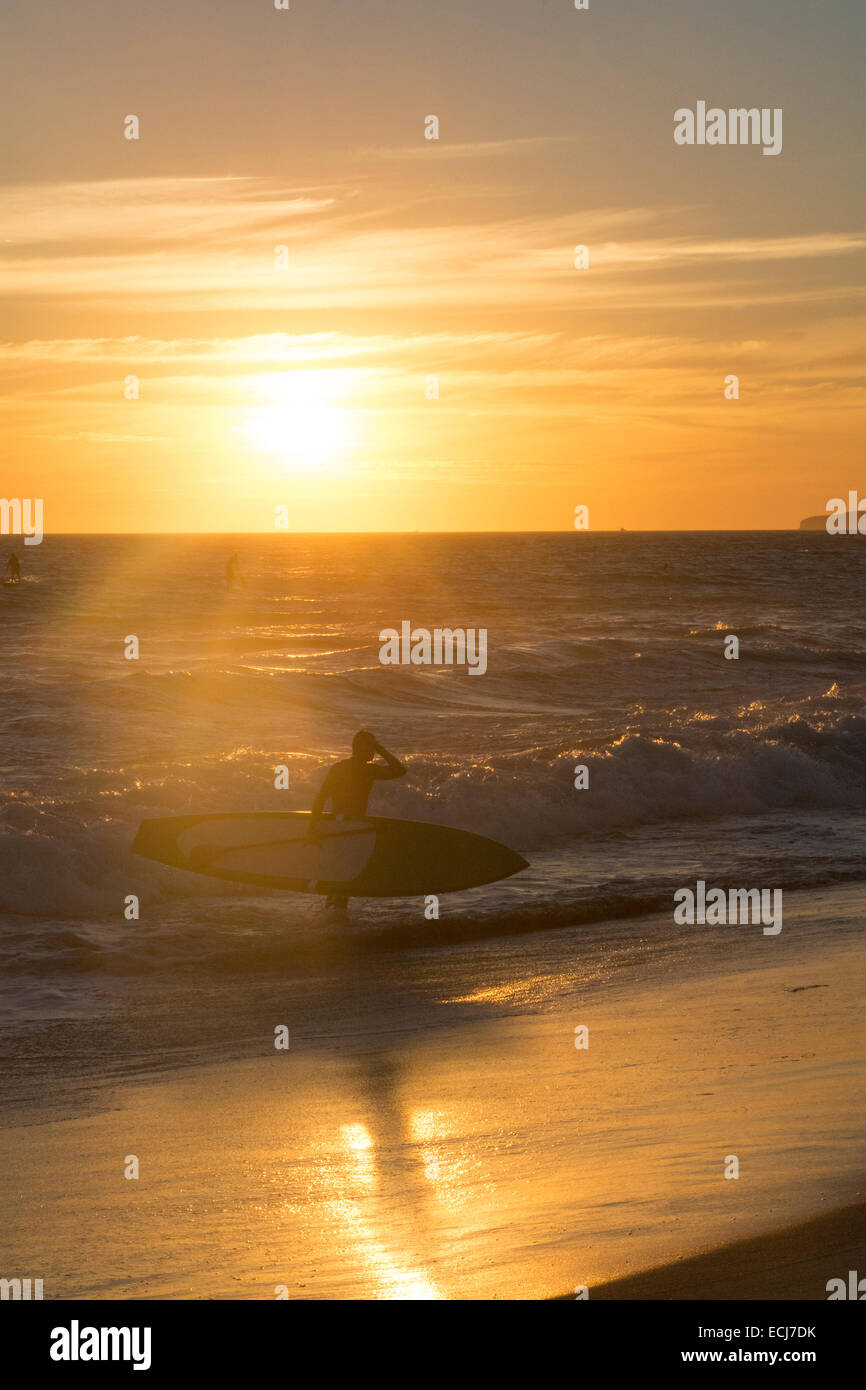 Stand-up paddleboarder retourne à la plage au coucher du soleil. Banque D'Images