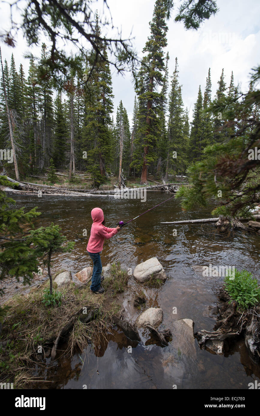 7-year-old girl poissons dans un ruisseau de montagne. Banque D'Images