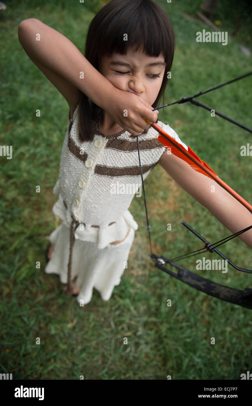 7-year-old girl tire un arc et une flèche. Banque D'Images